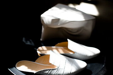white shoes on a black background in the style for blogging, a finger indicates shoes, a hand...