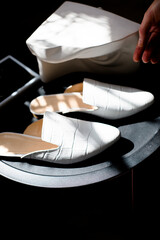 white shoes on a black background in the style for blogging, a finger indicates shoes, a hand...