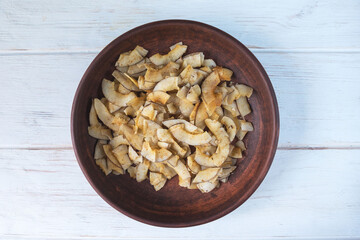 Delicious crispy coconut chips with salted caramel in a brown ceramic plate. Natural product made from coconut pulp. Useful snack for a snack. The concept of proper nutrition.