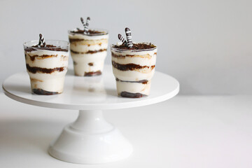 Classic tiramisu dessert in a glass and cup of coffee on light background. dessert with copy space closeup