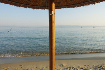 Wooden umbrella stub in middle of beautiful sea on sandy beach. Summer vacation wallpaper. Sea and sky background.