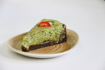 raw basil cheesecake with lime and mint close up on plate and light background. vegan dessert concept