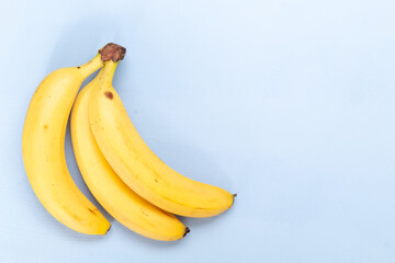 Bunch of fresh sweet organic bananas on light blue  background, empty space for text
