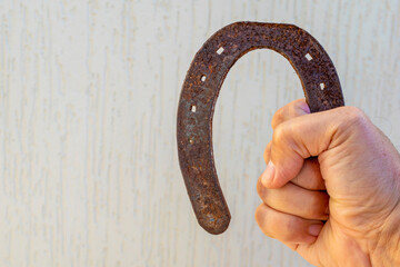 man hand holding old and rusty horseshoe with blurred white background and space for text