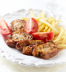 Fried pork tenderloin with french fries and tomatoes.  Close up. 