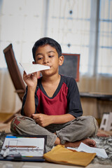 Boy playing handmade paper airplane at home quarantine