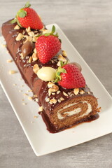 Chocolate cake roll with strawberries, nuts and cheese cream