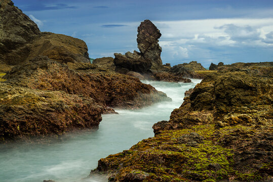 Beautiful view of Siung beach with rock tower and small water channel in long exposure shot