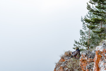a young girl of European appearance dressed in a poncho meditates in nature, sitting in the Lotus position on the edge of a cliff in the early morning, Zen