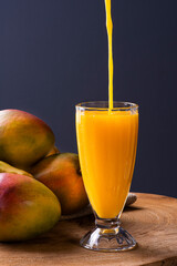 .Mango juice. Some mangos together on wooden background