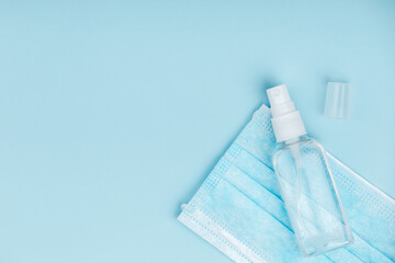 Hand sanitizer with medical mask on blue background.