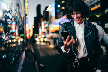 Carfree millennial influencer in earphones watching online video streams on modern cellphone...