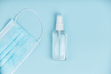Hand sanitizer with medical mask on blue background.