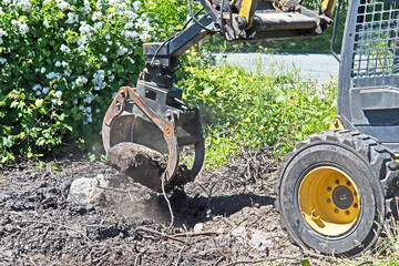 Fototapeta premium An excavator moves a large rock from the ground.