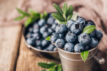 Blueberries in metal dishes on wooden table. Healthy eating and nutrition.