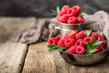 raspberries in metal dishes on wooden table. Healthy eating and nutrition.