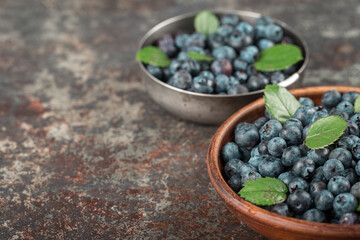 Blueberries in dishes on dark background. Healthy eating and nutrition.