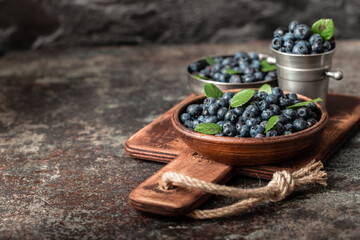 Blueberries in wood dishes on dark background. Healthy eating and nutrition.