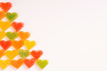 Multi-colored marmalade hearts in sugar on a white background. Marmalade sweets: Red, green and yellow sweet. Valentine's Day. Dessert. Copy space. View from above