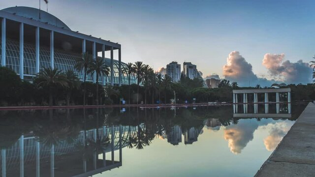 Sunrise time lapse in 4k at the Palau de la Música in Valencia, Spain with reflections of clouds.