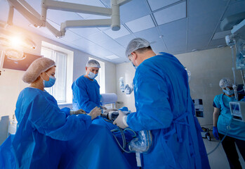 Group of surgeons in operating room with surgery equipment. Medical background, selective focus