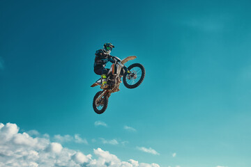 Fototapeta na wymiar Extreme concept, challenge yourself. Extreme jump on a motorcycle on a background of blue sky with clouds. Copy space, all or nothing.
