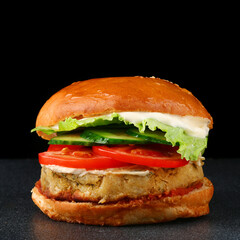 fresh tasty vegan burger on black isolated background. tomato, onion, vegan mayonnaise. Vegan chickpeas burgers with arugula, pickled cucumbers and hummus. Plant based diet concept.