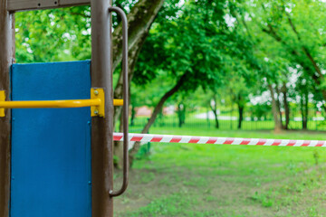 Children's playground on the green grass in the park wrapped with red barrier tape. Prohibition of...