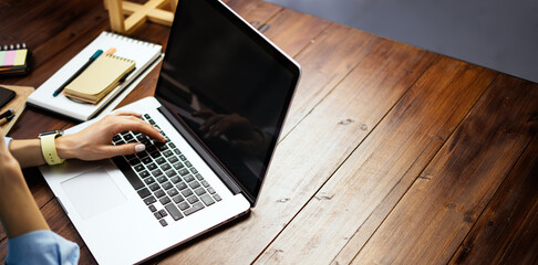 Mockup image of a woman using laptop with blank screen on wooden table