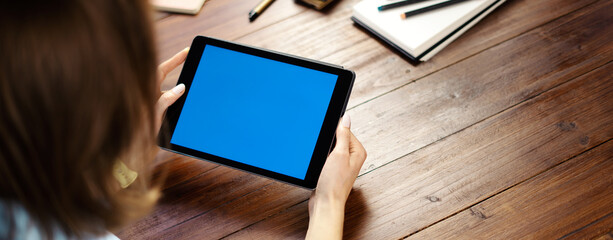 Mockup image of a woman using digital tablet with blank screen on wooden table. Close up photo of...