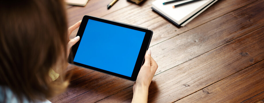 Mockup image of a woman using digital tablet with blank screen on wooden table. Close up photo of female hands holding device horizontally