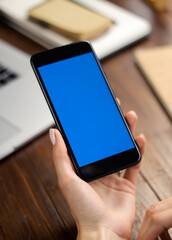 Mockup image of a woman using smartphone with blank screen on wooden table