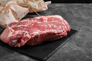 Pork tenderloin, freshly meat on a slate plate on a gray background with vegetables. copy space, photo for grocery stores