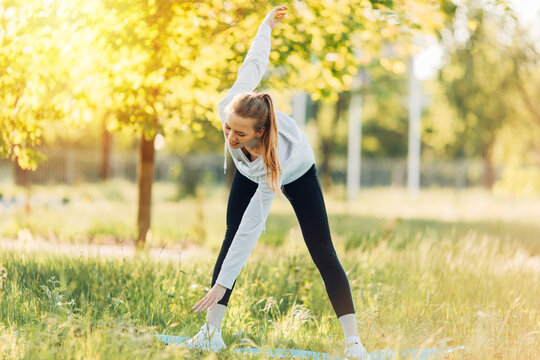 Photo of a beautiful young athlete in a Park doing a stretch