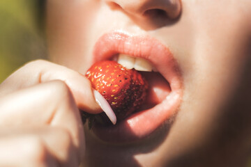 girl with beautiful lips bites strawberries