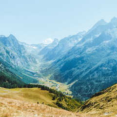 Hilly mountains against a cloudless blue sky. Snowy peaks. Coniferous forest in the foreground and the river in the distance. Tourism, travel, climbing, mountaineering. trekking