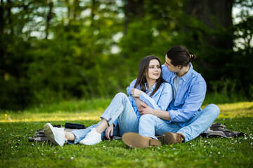 Fototapeta premium Young in loved couple sitting on the grass in a summer garden