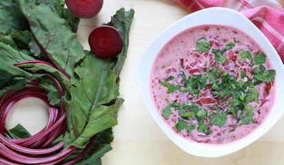 Fresh beetroot soup with beets on wooden table flat lay top view