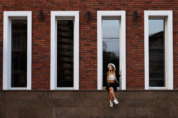 The girl is sitting on the window outside. background with people