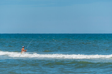 Man Surf Fishing in Water at Beach