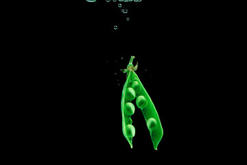 Fresh pea dropped into a water on dark background isolate.