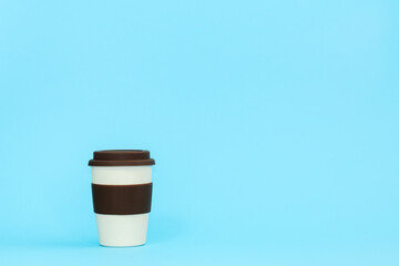 A cup of bamboo, environmentally friendly, on a blue background. Light cup with a brown lid.