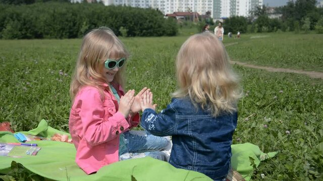 Two sisters play hands in the park on the grass in summer hd