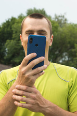 young man with a phone in his hands smiling on a park background