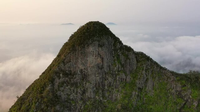 Aerial shot of famous Mount Warning by cloudscape against sky, drone flying forward over natural landscape