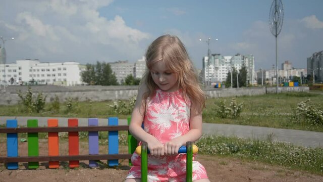 Happy cute little girl swinging on a swing against the background urban landscape hd