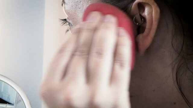 young woman applying make up with sponge