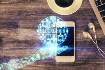 Fototapeta na wymiar Double exposure of blockchain theme hologram over table with phone. Top view. Crypto technology concept.