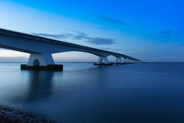 Zeeland Bridge - long white bridge over the river, beautiful blue sky with dynamic clouds. Long time, calm water of the Oosterschelde ..