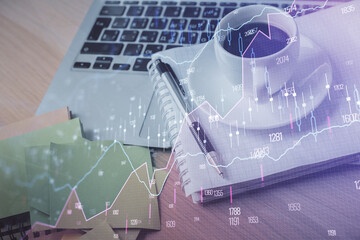 Double exposure of forex chart drawing and desktop with coffee and items on table background. Concept of financial market trading